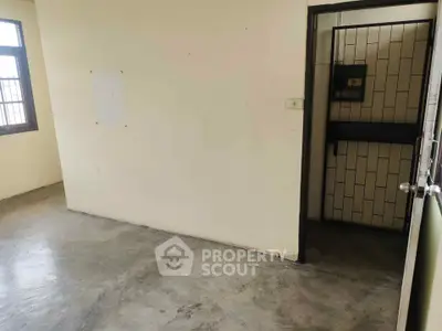 Spacious empty room with concrete floor and large window, ideal for customization.