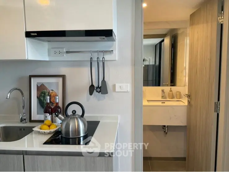 Modern kitchen with sleek design and adjacent bathroom, featuring contemporary fixtures and stylish decor.