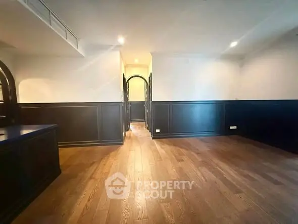 Spacious living room with elegant wood flooring and classic wainscoting.