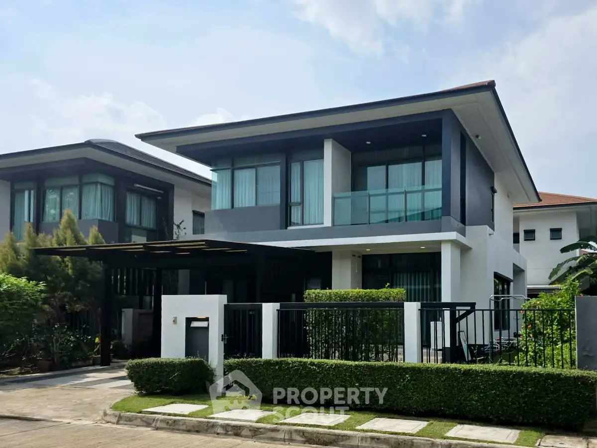 Modern two-story house with sleek design and manicured garden in a suburban neighborhood.