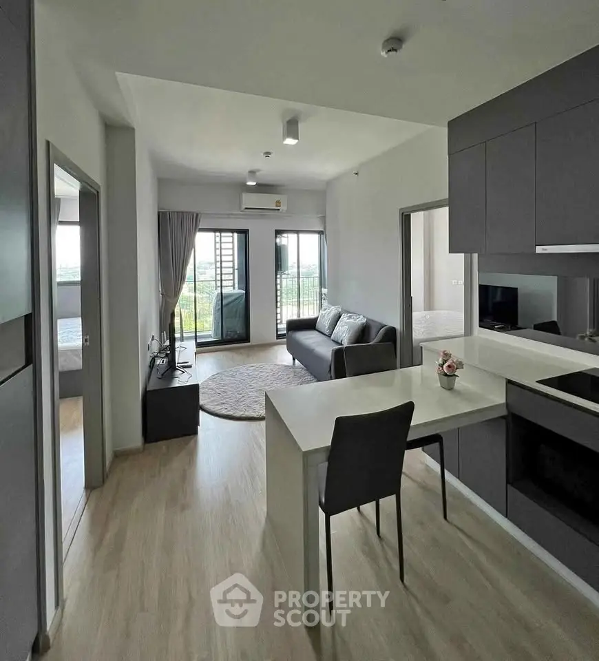 Modern open-plan living room with sleek kitchen and balcony view