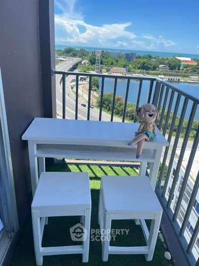Charming balcony with scenic river view, featuring cozy seating and lush artificial grass flooring.