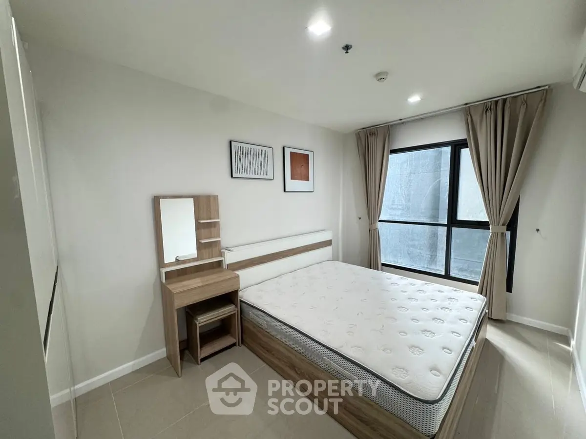 Spacious bedroom with modern furnishings and large window for natural light.