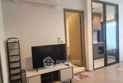 Modern living room with TV, air conditioning, and open bathroom access in stylish apartment.