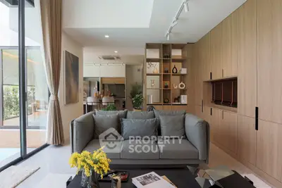 Modern living room with stylish decor and open kitchen layout, featuring a cozy sofa and elegant shelving.