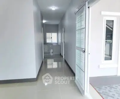 Bright hallway with glossy tiled floor and modern glass door in a contemporary home.