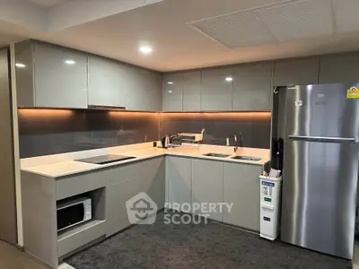 Modern kitchen with sleek cabinets, stainless steel fridge, and built-in microwave in a stylish apartment.