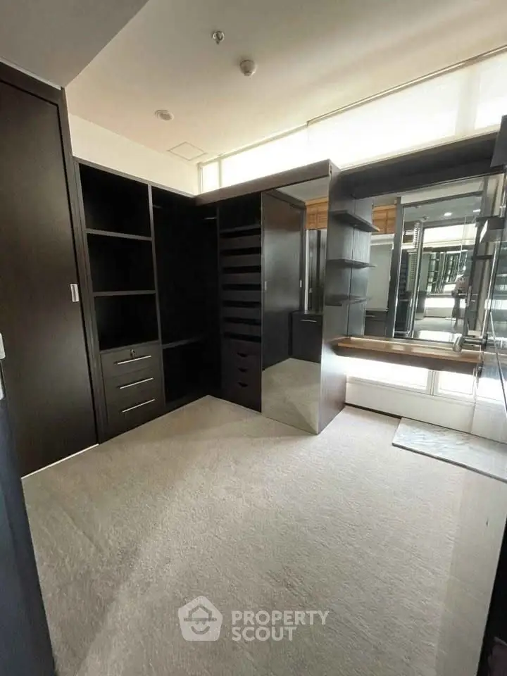 Spacious walk-in closet with modern dark wood shelving and ample storage space.