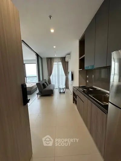 Modern open-layout apartment with sleek kitchen and cozy living area, featuring large windows and stylish decor.