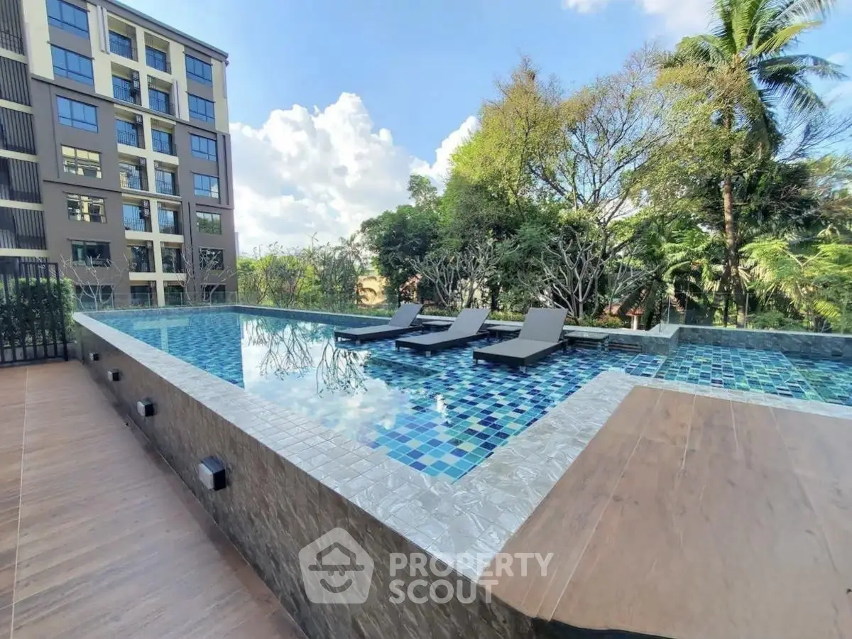 Luxurious rooftop pool with sun loungers and scenic views in modern apartment complex.