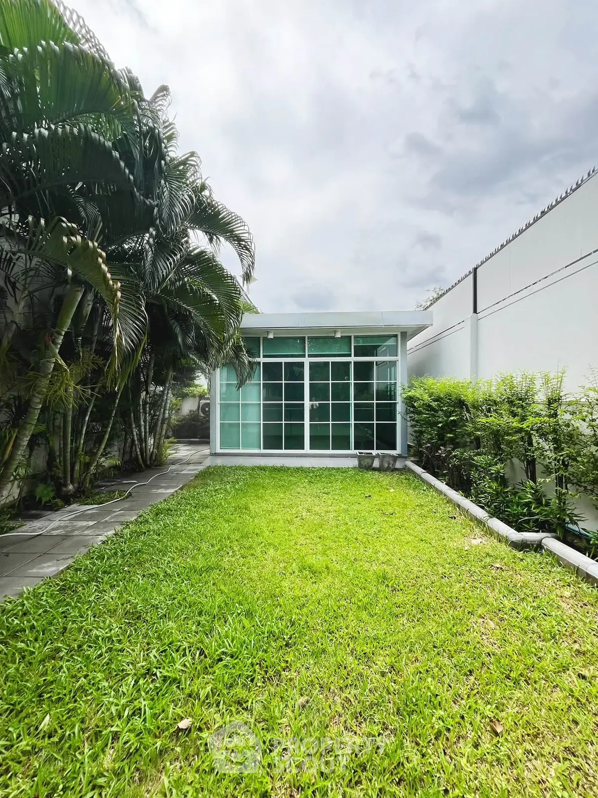 Modern garden view with lush greenery and sleek glass facade, perfect for serene living.