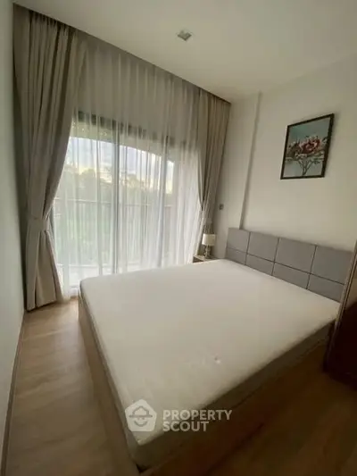 Cozy bedroom with large window and elegant curtains, perfect for natural light lovers.