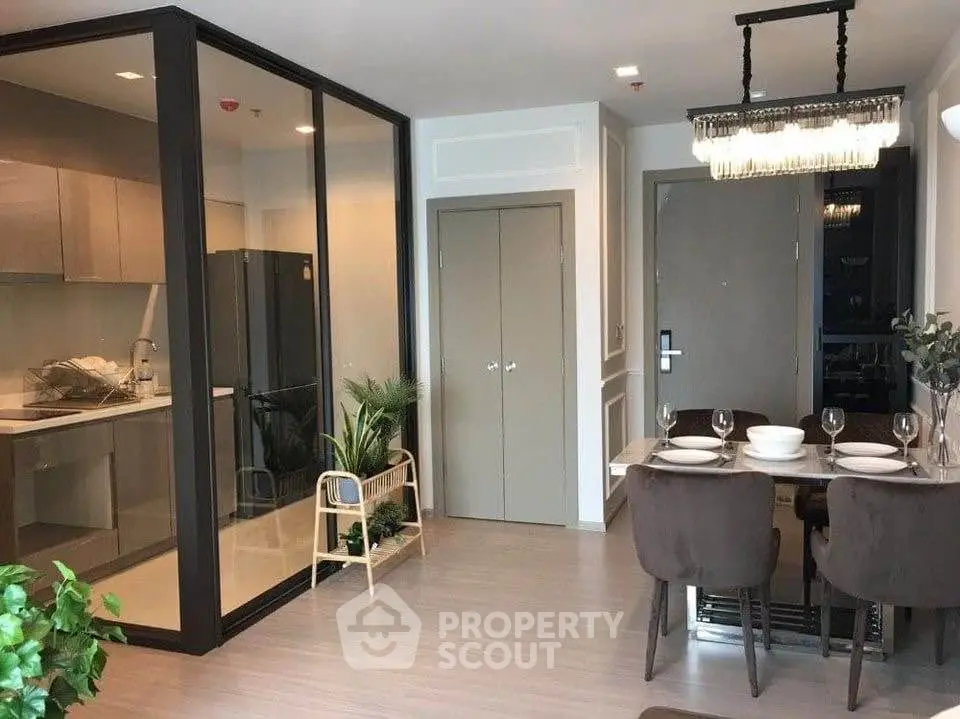 Modern open-plan living and dining area with glass partition kitchen in stylish apartment.