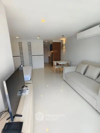 Modern living room with sleek furniture and open layout, featuring a cozy sofa and flat-screen TV.