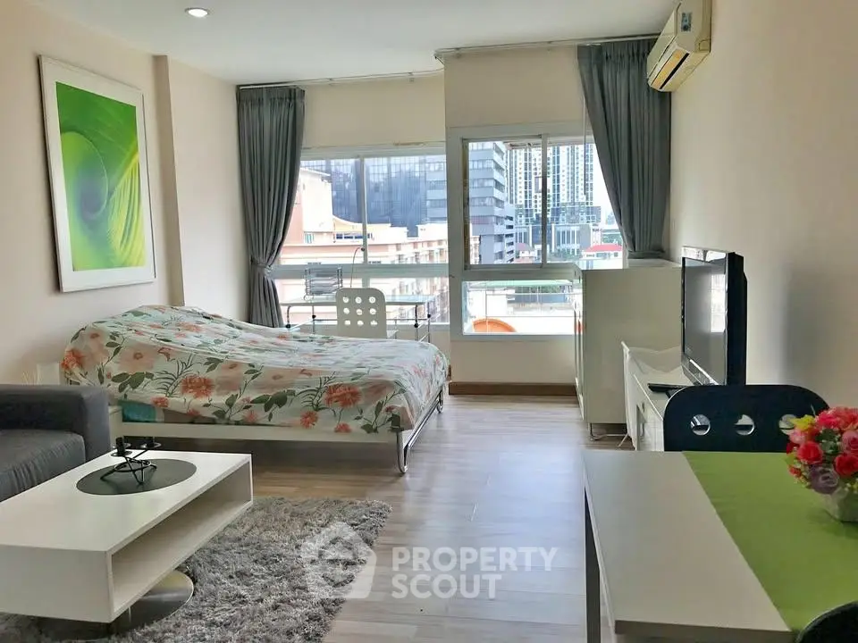 Modern studio apartment with stylish decor and city view, featuring cozy living area and large windows.