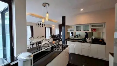 Spacious modern kitchen with open layout and elegant dining area, featuring sleek black countertops and stylish lighting.