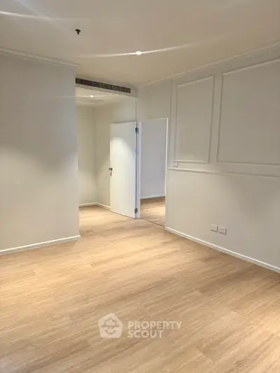 Spacious empty room with wooden flooring and white walls, perfect for customization.