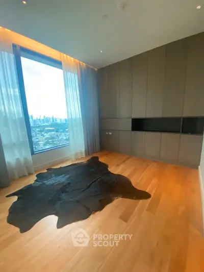 Spacious modern room with large window offering stunning city skyline view, featuring elegant wood flooring.