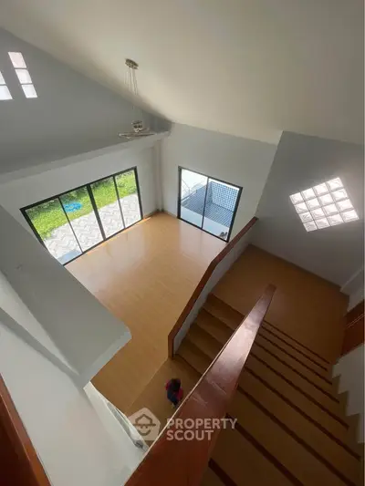 Spacious modern living room with high ceiling and large windows overlooking garden