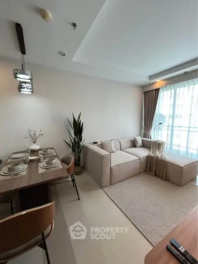 Modern living room with cozy beige sofa and elegant dining area in a bright apartment.