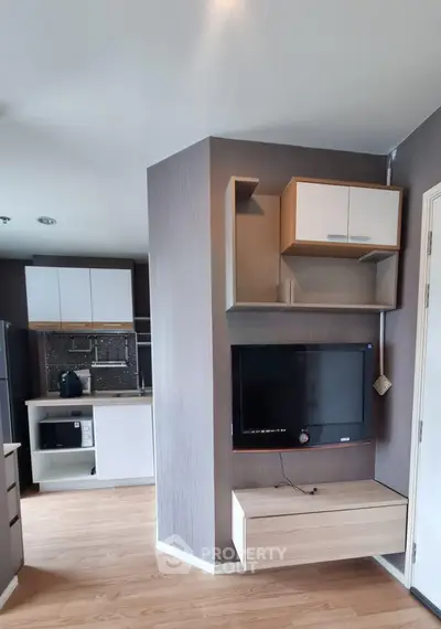Modern living room with wall-mounted TV and sleek kitchen in open layout