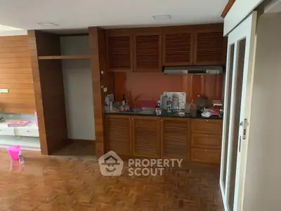 Spacious kitchen with wooden cabinets and parquet flooring, ideal for modern living.