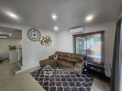 Modern living room with stylish decor and comfortable leather sofa, featuring large window and elegant wall clock.