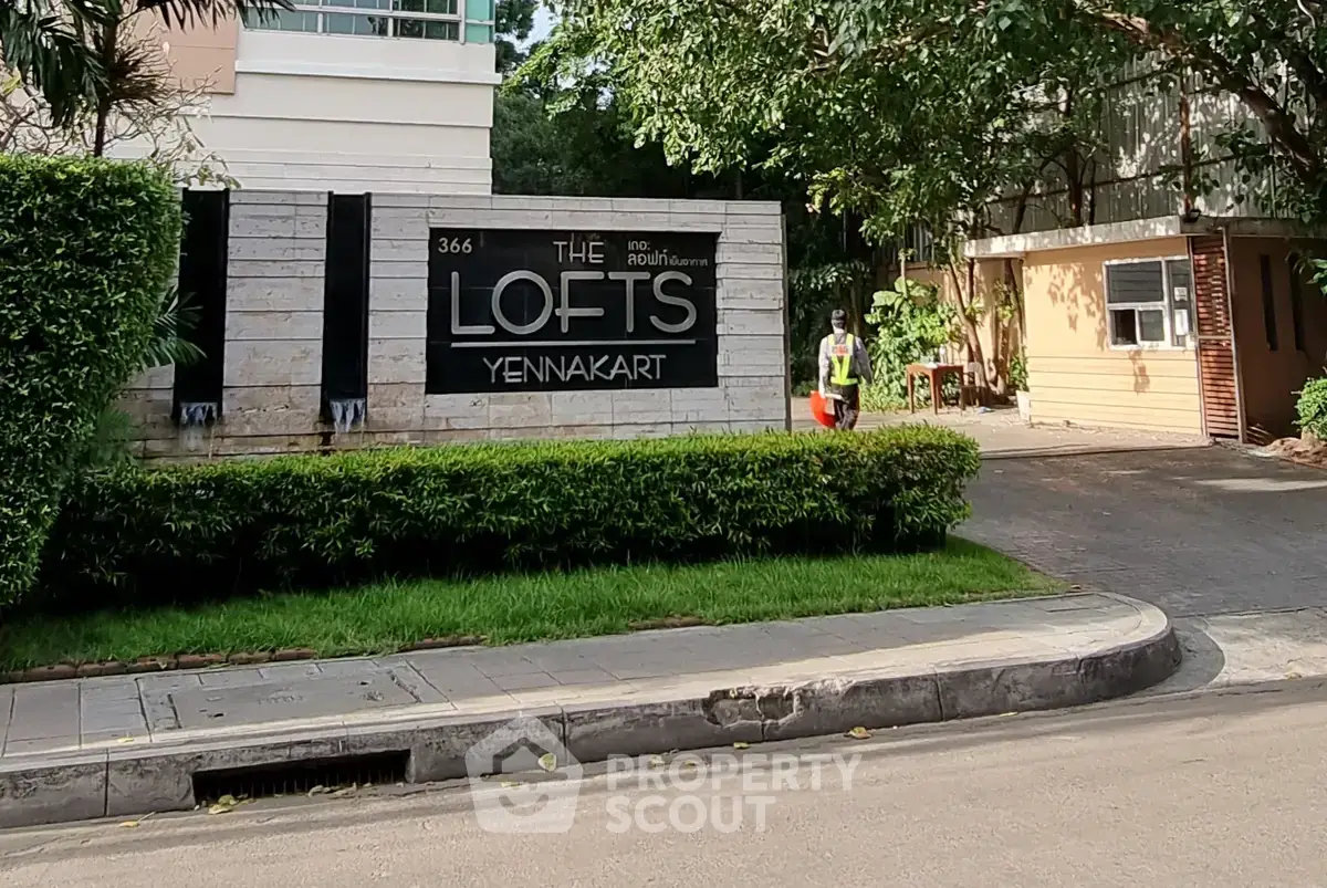 Modern residential building entrance with lush greenery at The Lofts Yennakart.