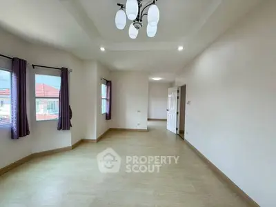 Spacious empty living room with modern lighting and large windows.