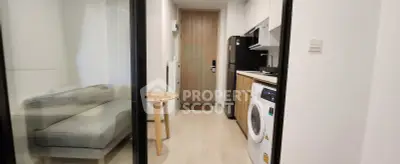 Modern apartment interior with compact kitchen and cozy living area, featuring a washing machine and sleek design.