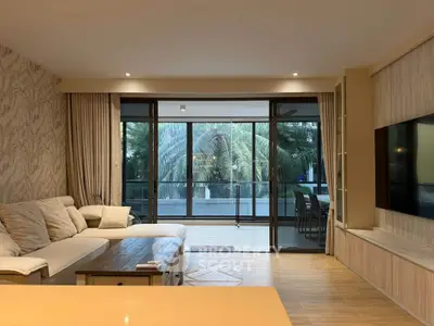 Spacious living room with modern decor and large balcony overlooking lush greenery.