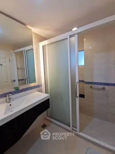 Modern bathroom with sleek shower and elegant vanity in contemporary home.