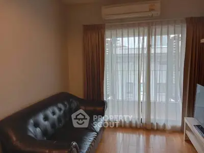 Cozy living room with leather sofa and large window with curtains