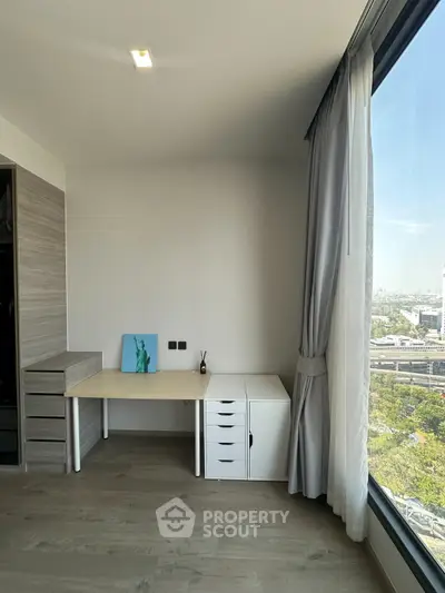 Modern study room with large window offering stunning city view, featuring sleek desk and storage cabinets.