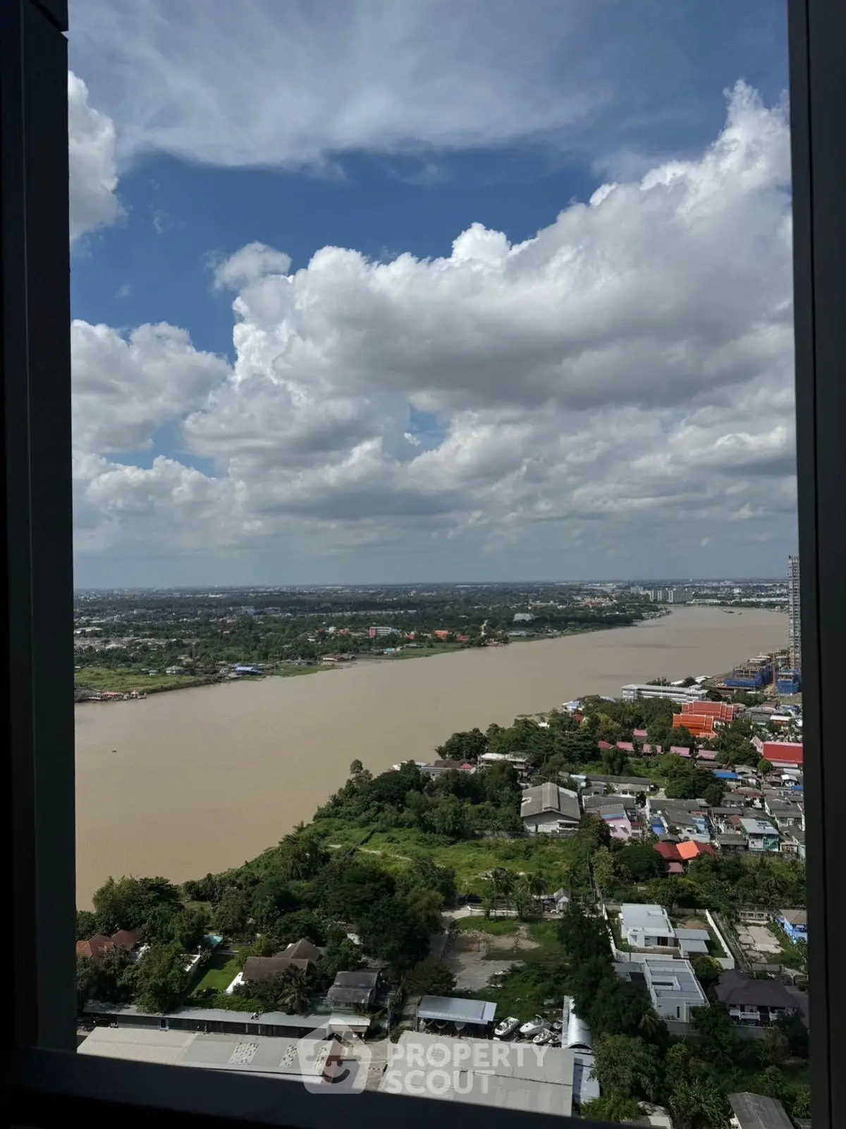 Stunning river view from high-rise window showcasing expansive cityscape and lush greenery.