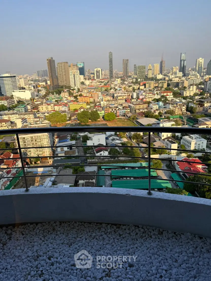 Stunning cityscape view from a high-rise balcony with modern railing and pebble flooring.