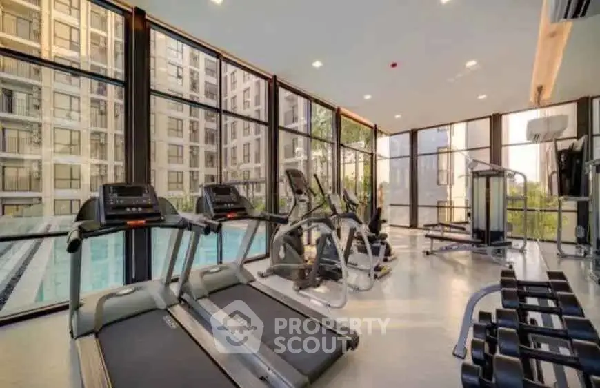 Modern gym with state-of-the-art equipment and pool view in luxury apartment complex.