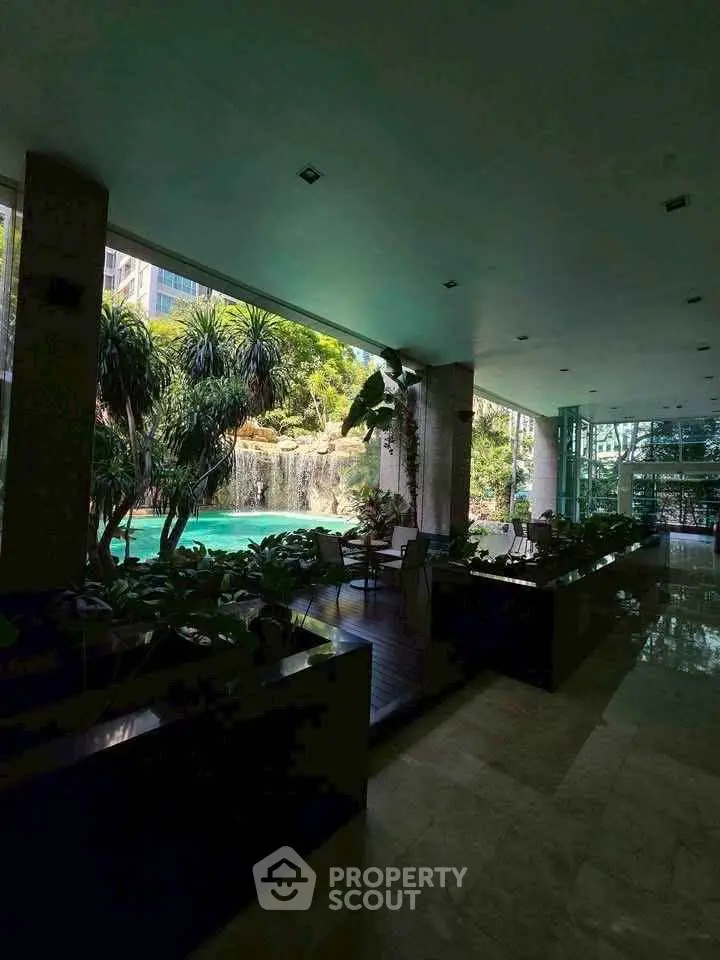 Luxurious indoor pool area with lush greenery and waterfall view, perfect for relaxation and leisure.