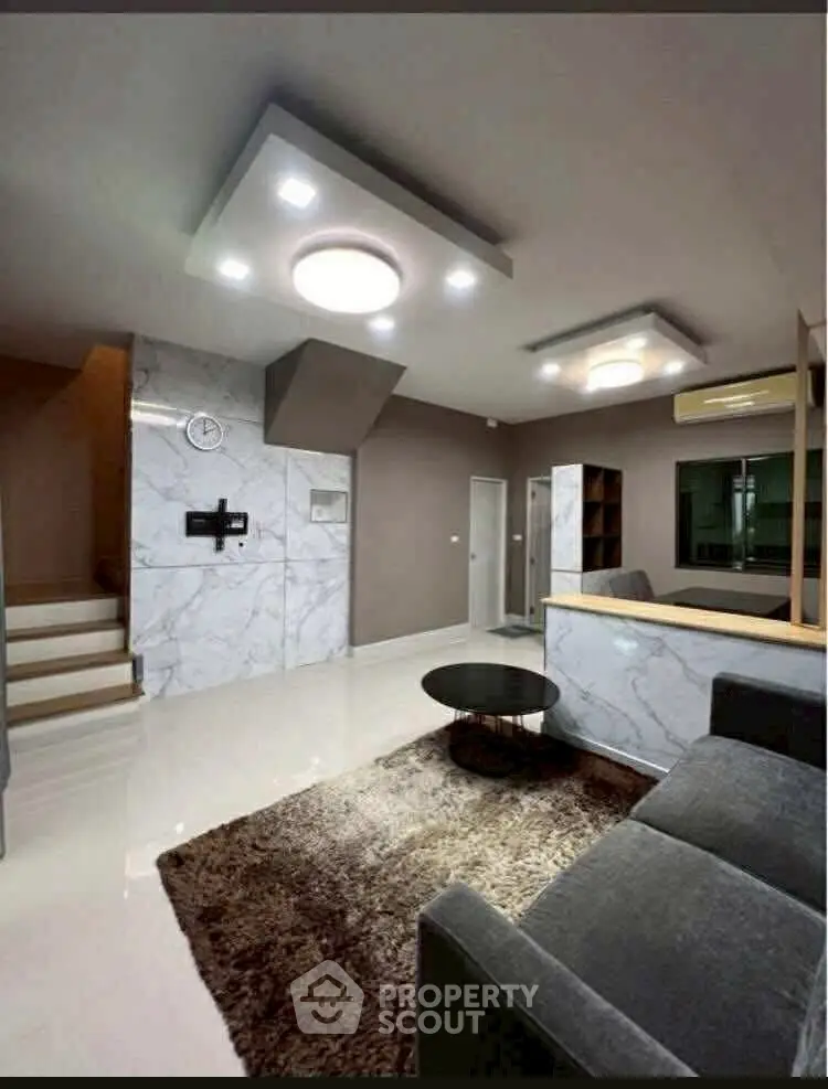 Modern living room with stylish lighting and marble accents, featuring a cozy seating area and elegant decor.