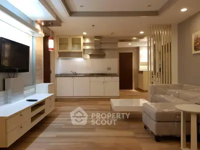Modern living room with open kitchen, sleek furniture, and wooden flooring in a stylish apartment.
