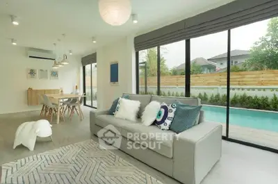 Spacious living room with pool view, modern decor, and ample natural light in a luxury home.