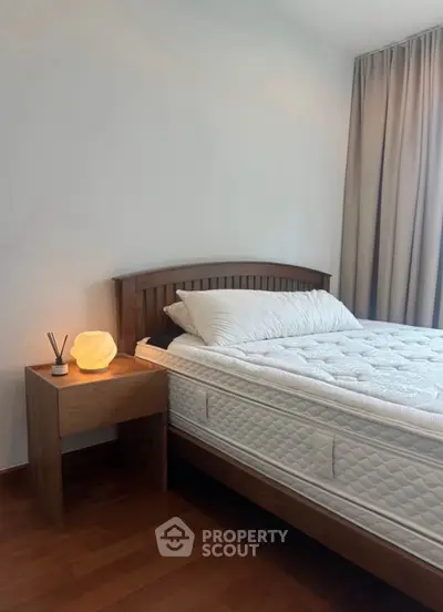 Cozy bedroom with wooden bed frame and soft lighting, perfect for relaxation.