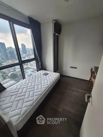 Cozy bedroom with city view, featuring a single bed and modern furnishings in a high-rise apartment.