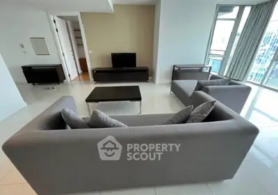 Spacious modern living room with sleek gray sofas and large windows offering city views.