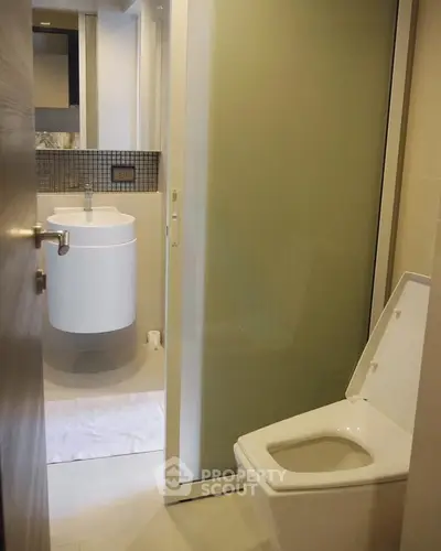 Modern bathroom with sleek fixtures and frosted glass door in a contemporary apartment.