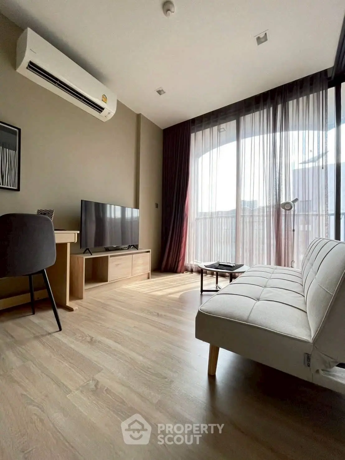 Modern living room with natural light, featuring sleek furniture and a large window with city view.