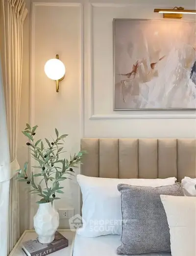 Elegant bedroom corner with plush headboard, modern art, and soft lighting for a cozy ambiance.