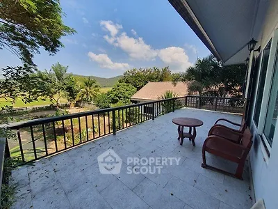 Spacious balcony with scenic view of lush greenery and mountains, perfect for relaxation.