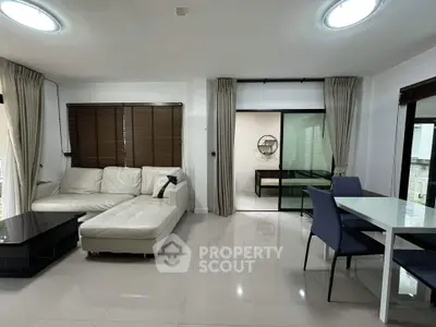 Spacious modern living room with white sectional sofa and dining area, perfect for entertaining.