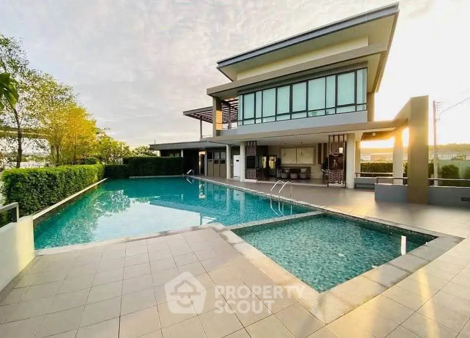 Luxurious modern house with stunning pool and spacious outdoor area at sunset.